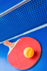 old pingpong racket and a dented ball on a blue pingpong table