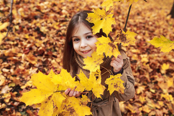 Naklejka na ściany i meble Little Girl Plays In The Autumn Leaves in park