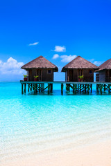 Water villas on wooden pier in turquoise ocean on the white sand beach - 216511811