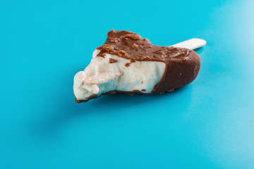 side view chocolate outer ice cream with some bites on a blue background close up