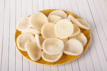 Rice crisps on a wooden plate. The background is white.