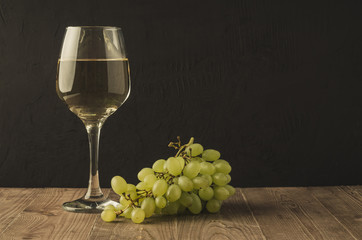 wineglass with white wine and grape/wineglass with white wine and grape on a dark background, copy space