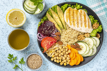 Bowl of Buddha, The concept of a healthy diet: grilled chicken, avocado, chickpeas, kinua, carrots, tomatoes, nuts. Balanced food. Top view. Copy space.