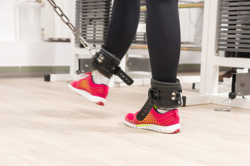 Woman wearing leather ankle straps in a gym