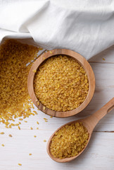 Dry bulgur wheat in  bowl and spoon