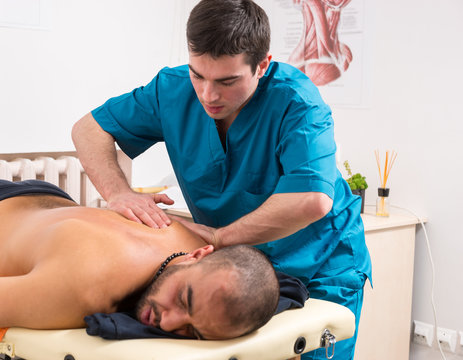 Masseur kneading the back muscles of a client