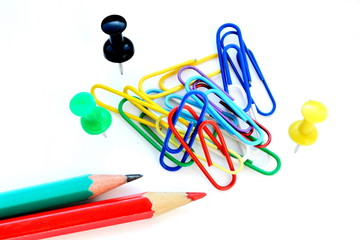 colorful sharp pencils, paper clips and office pins on white background