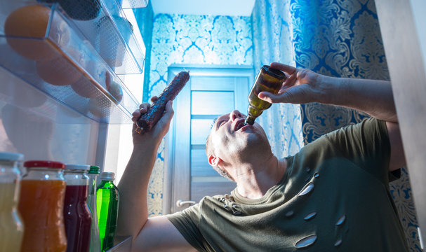 Man slugging back a beer from his fridge