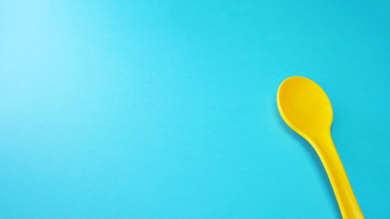 Yellow plastic spoon at green background isolated