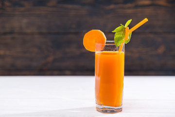 Glass of carrot juice with mint leaf on straw
