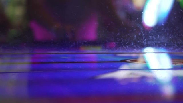 Slo-motion low angle shot of an air hockey table, with the player in the background.