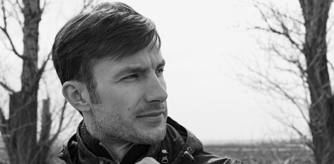 Portrait of a cheerful businessman on a background of trees in a field.