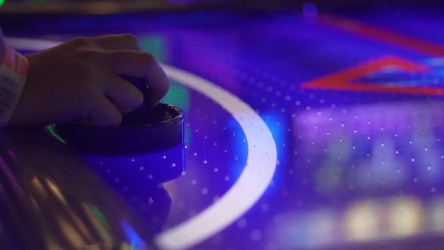 Slo-motion, side shot of a girl's hand playing air hockey.