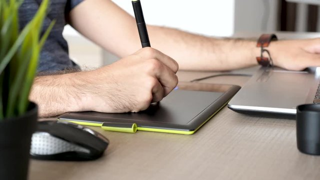 Graphic artist working on a digital tablet. Close up footage of man using a digitiser