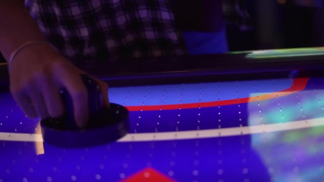 4K shot of a girl playing air hockey. You see her hand as she hits the puck around and then eventually into her own goal on accident.