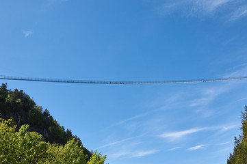 Suspension bridge over the precipice. Blue sky, people are standing. Germany, highline179. 