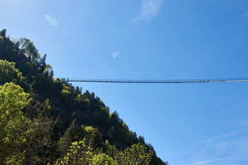 Suspension bridge over the precipice. Blue sky, people are standing, trees. Germany, highline179. 