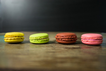 Cake macaron or macaroon on wooden table with black background, sweet and colorful dessert