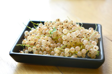 white currants on a black plate on wooden table