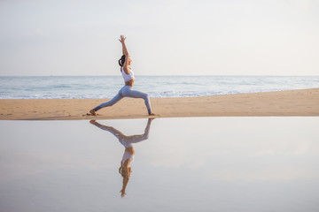 Caucasian woman practicing yoga at seashore of tropic ocean