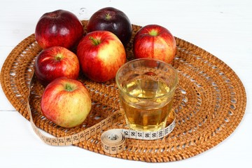 Apple vinegar good for diet / Fersh apples, measuring tape, cut bottle and glass on white wooden table