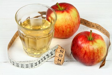 Apple vinegar good for diet / Fersh apples, measuring tape, cut bottle and glass on white wooden...
