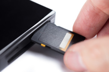 Hand inserting SD memory card into card reader, isolated on white background