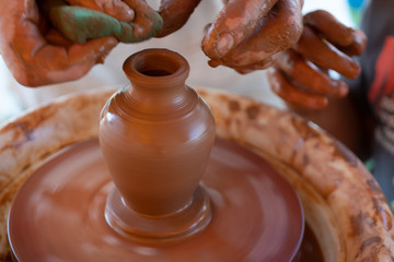 The master's hands make a pot on the potter's wheel.