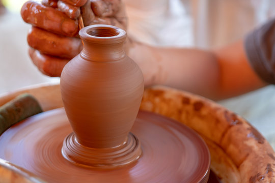 The master's hands make a pot on the potter's wheel.
