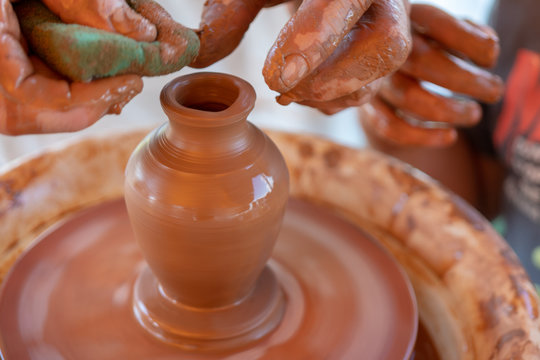 The master's hands make a pot on the potter's wheel.