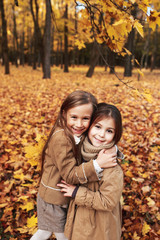 Fototapeta na wymiar Cute two little sisters hugging in autumn park outdoor