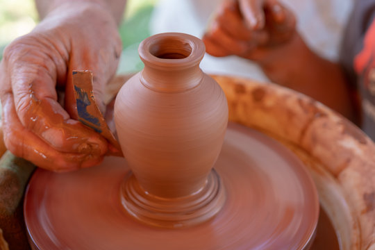 The master's hands make a pot on the potter's wheel.