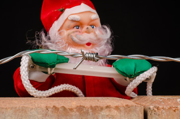 Santa trying to climb the wall, a concept on immigration policies.