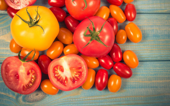 Different varieties of tomatoes on a blue wooden background.
