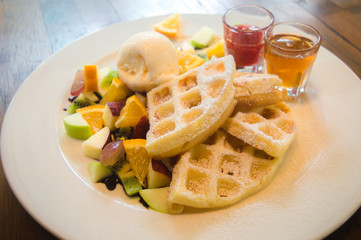 Fruit salad on a plate and waffle came with ice cream.