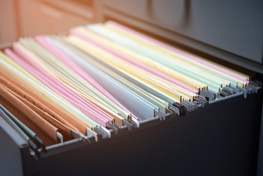 Colorful Business Documents Are Placed In A Filing Cabinet In The Office.