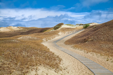 Dunes with wooden walkway over sand near Baltic sea. Board way over sand of beach dunes in Lithuania.