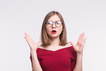 Portrait of shocked girl with red lips in glasses with hands up.