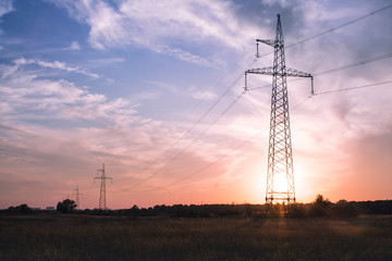 Electricity transmission towers line on beautiful soft colors sunset or sunrise background No people