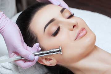 The cosmetologist makes the procedure Microdermabrasion of the facial skin of a beautiful, young...