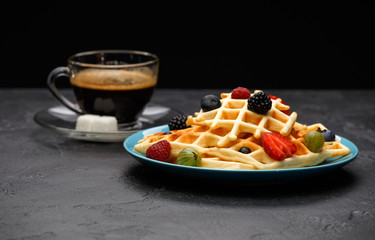Photo of cup of black coffee with sugar with Viennese waffles with strawberries, raspberries