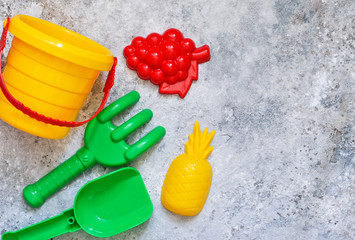 Children's toys: bucket, shovel, rake on a stone background. Toys for the beach.