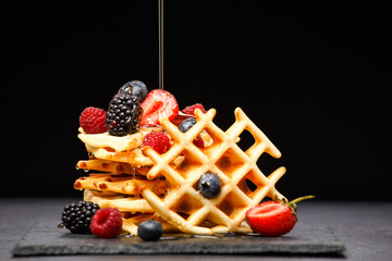 Photo of viennese wafers with berries pouring honey on black empty background