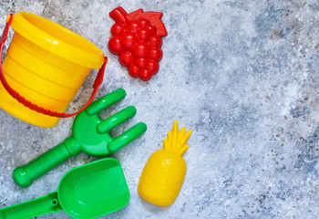Children's toys: bucket, shovel, rake on a stone background. Toys for the beach.