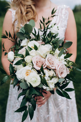 Naklejka premium Bride in white wedding dress with a beautiful bouquet of roses