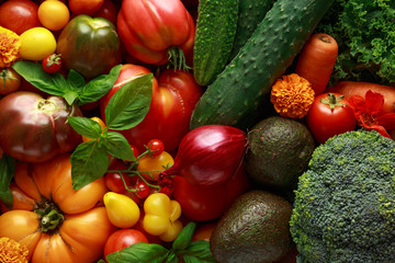 Organic Vegetable box with large, cherry tomatoes, basil, cucumbers, red onions, broccoli and avocado.