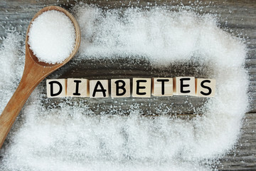 Diabetes word on wooden letters with crystalized white sugar as frame 

