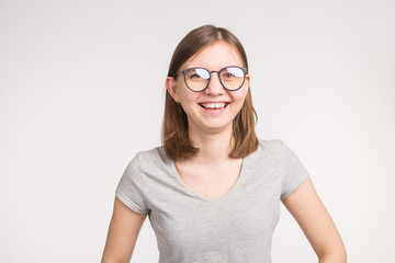 Fashion, emotions, people concept - young happy woman in glasses smiling over the white background