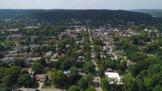 A slow forward aerial establishing wide shot of the residential district of a small town in western Pennsylvania on a summer day. Pittsburgh suburbs.  	