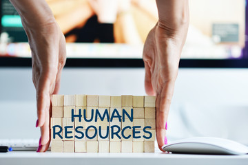 Business human resources concept with wooden cubes in front of office computer
